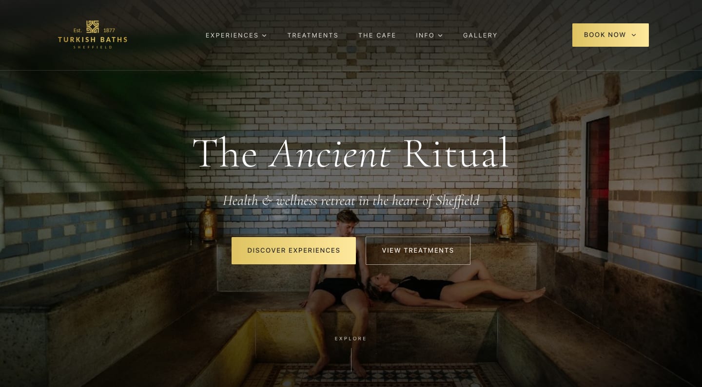 The Turkish Baths 1877 homepage: the tiled steam room behind the heading “The Ancient Ritual”, with Discover experiences and View treatments buttons.